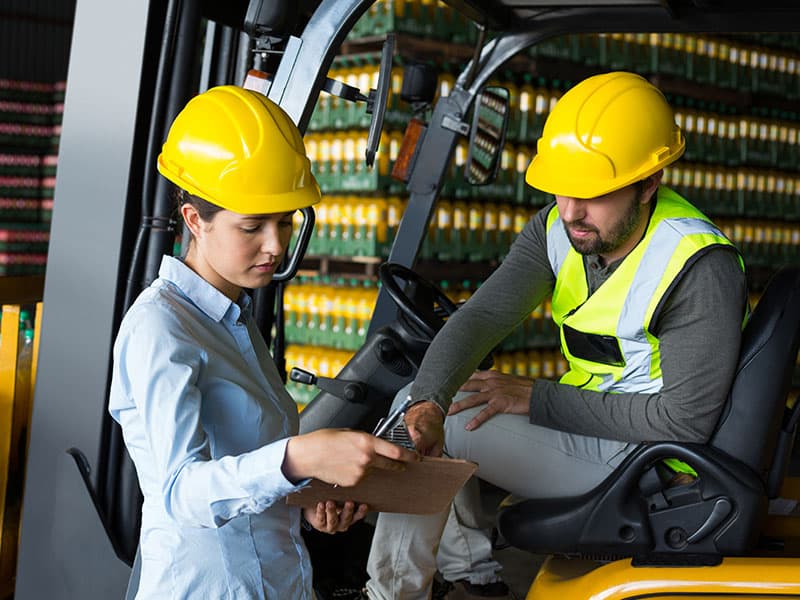 Brennan Blog Forklift Maintenance Tips Factory Workers Checking Record On Clipboard In Warehouse | Brennan Equipment Services